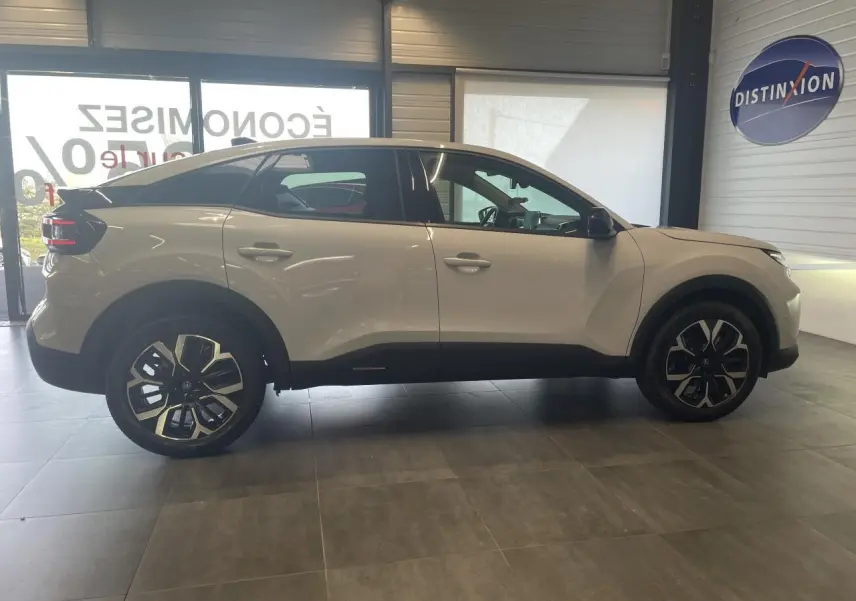 Vue de profil côté gauche d'une Citroën C4 blanche métallisée avec jantes alliage 18 pouces en showroom.