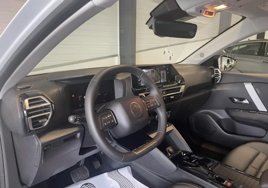 Vue intérieure côté conducteur de la Citroën C4 2025 avec tableau de bord noir et écran tactile central.