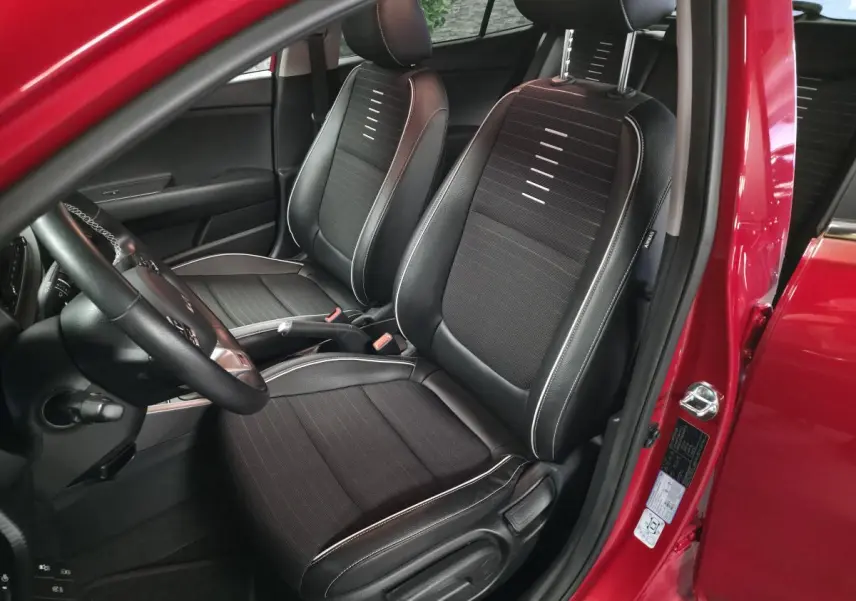 Vue intérieure côté conducteur de la KIA Rio rouge 2022, sièges bi-ton cuir tissu noir avec surpiqûres grises.