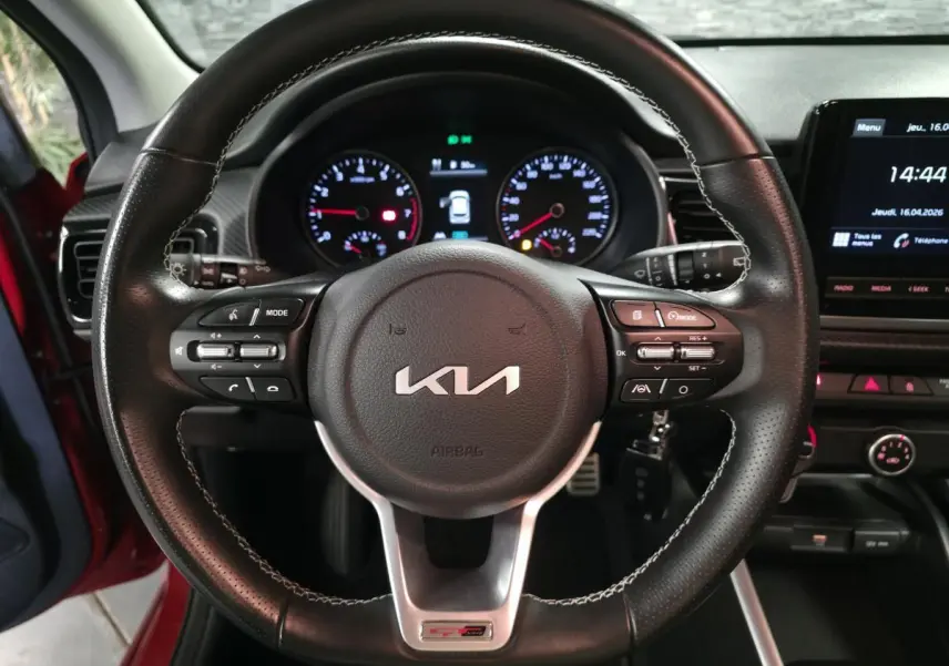 Vue rapprochée du volant cuir perforé noir de la KIA Rio GT Line 2022 avec commandes intégrées et tableau de bord digital.