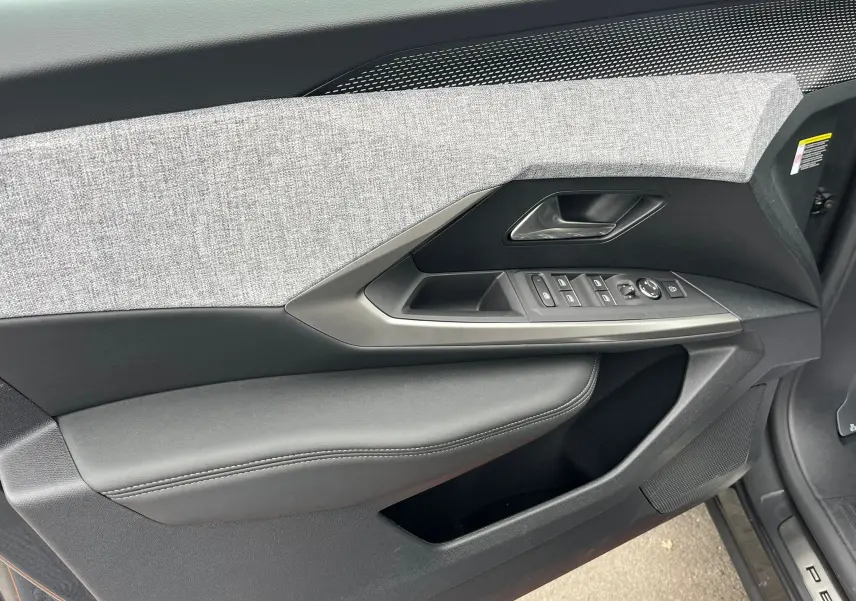 Gros plan sur la porte côté gauche du Peugeot 3008 gris titane, avec garniture tissu gris et commandes électriques intégrées.