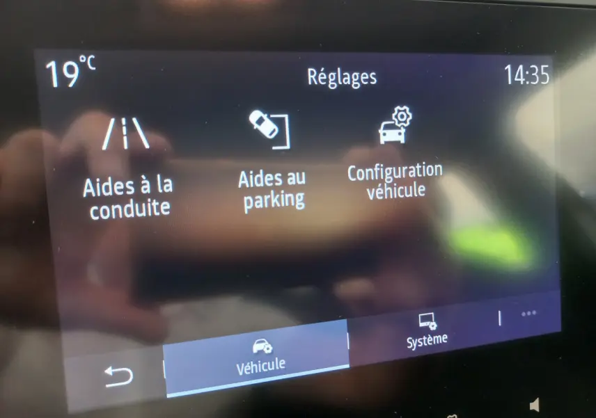 Écran tactile central de la Renault Clio Business blanc 2021 affichant les réglages d'aides à la conduite et parking.