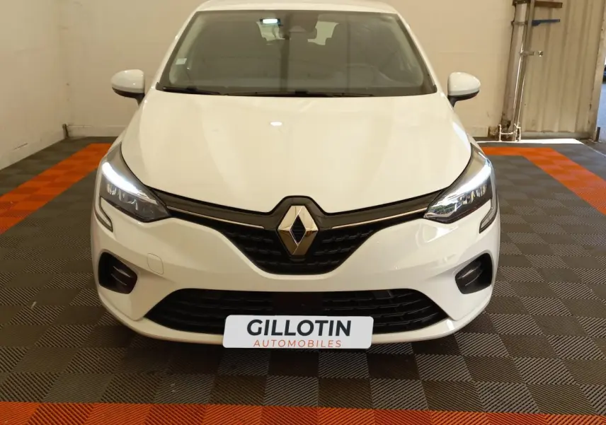 Vue frontale d'une Renault Clio Business SCe 65 blanche avec phares LED allumés dans un garage.