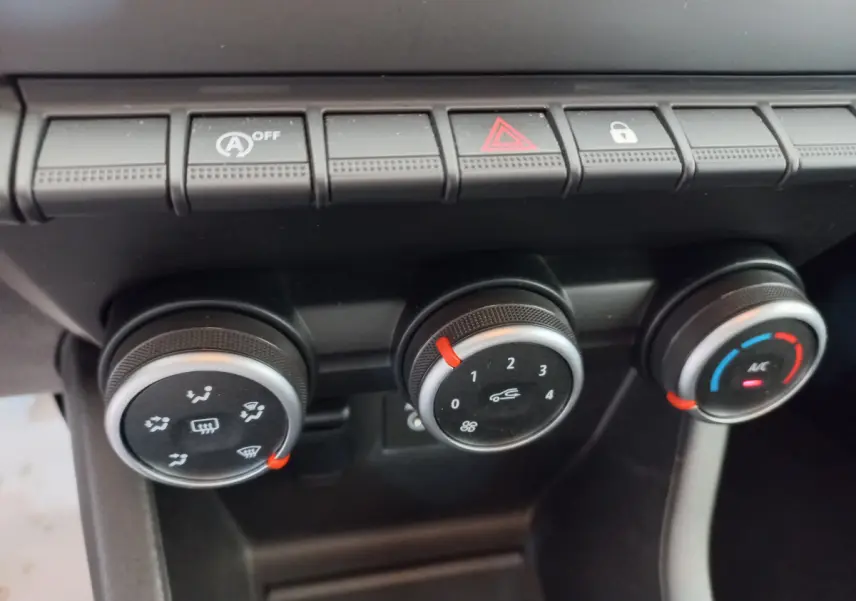 Gros plan sur les commandes de climatisation et boutons de fonction du tableau de bord noir de la Renault Clio Business blanche 2021.