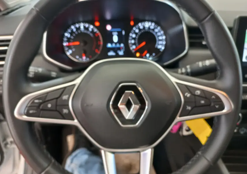 Vue rapprochée du volant cuir noir multifonctions de la Renault Clio Business blanche, avec commandes intégrées.