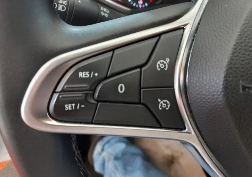 Gros plan sur les commandes de régulateur de vitesse au volant cuir synthétique d'une Renault Clio Business blanche 2021.