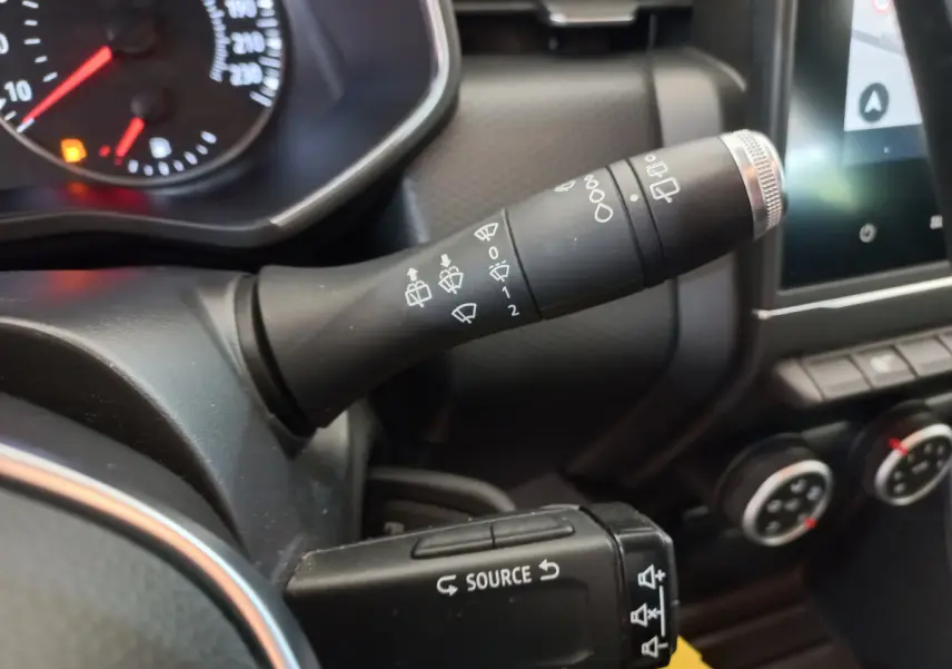 Gros plan sur les commandes de phares et essuie-glaces du tableau de bord de la Renault Clio Business blanche 2021.