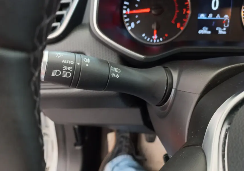 Gros plan sur la commande des feux et le tableau de bord numérique de la Renault Clio Business blanche de 2021.