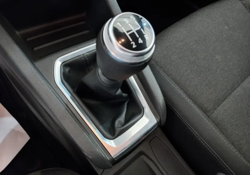 Gros plan sur le levier de vitesses manuel noir et argenté de la Renault Clio Business blanche, avec siège tissu gris à côté.