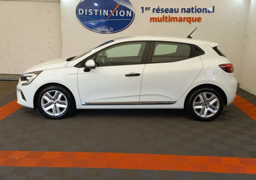 Profil côté droit d'une Renault Clio Business blanche de 2021, avec jantes alliage et vitres teintées, en intérieur showroom.