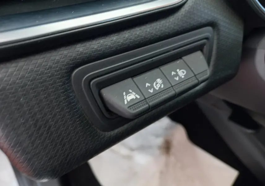 Gros plan sur les boutons de réglage d'assistance à la conduite dans l'habitacle noir d'une Renault Clio Business blanche.