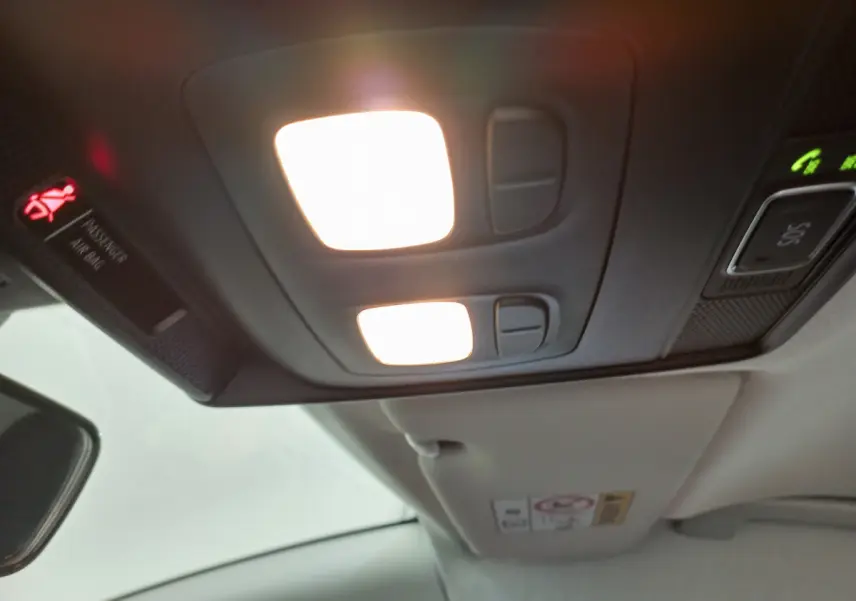 Plafonnier intérieur allumé avec commandes, visière pare-soleil et rétroviseur d'une Renault Clio Business blanche 2021.