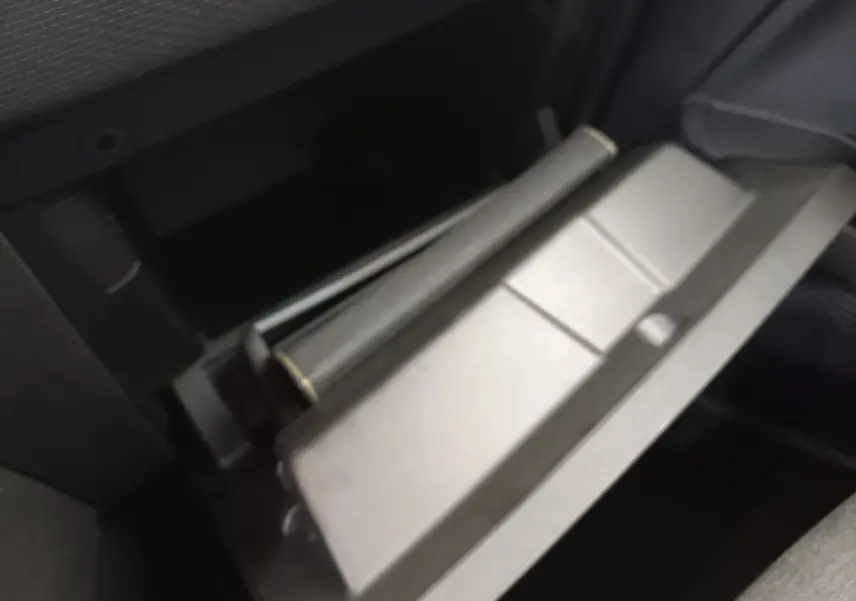 Gros plan sur le rangement ouvert côté passager de la Renault Clio Business blanche, intérieur sombre visible.