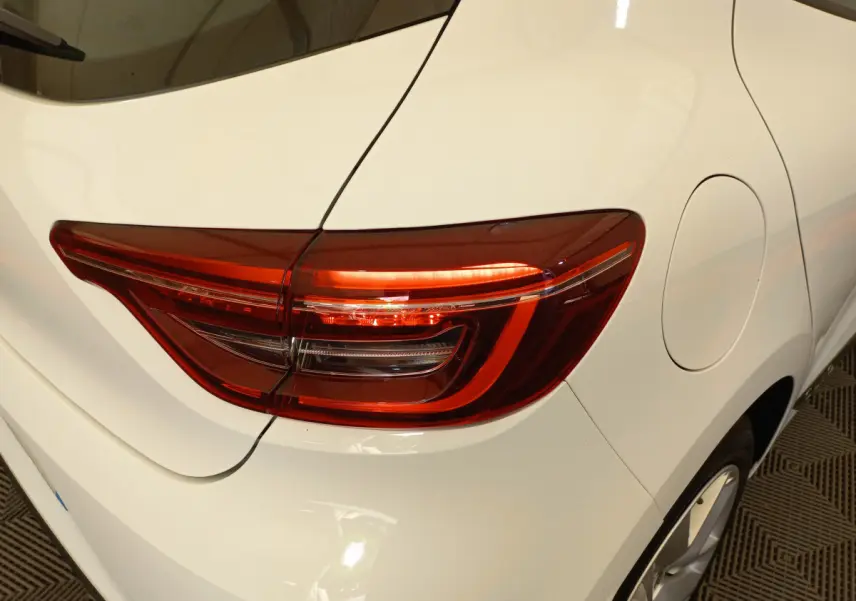Gros plan sur le feu arrière droit d'une Renault Clio Business blanche, mettant en valeur la carrosserie lisse et la trappe à carburant.