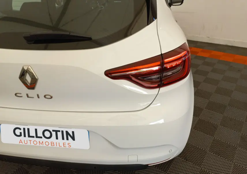Vue arrière droite d'une Renault Clio Business blanche avec feux arrière LED et logo distinctif sur coffre.