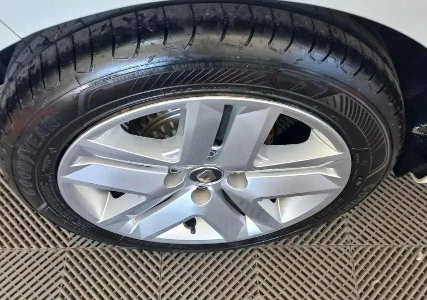 Gros plan sur la roue avant droite d'une Renault Clio blanche, mettant en valeur la jante alliage et le pneu Goodyear.