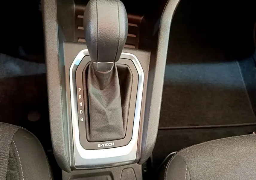 Gros plan sur le levier de vitesses automatique noir avec marquage E-TECH dans l'habitacle sombre de la Renault Clio hybride.