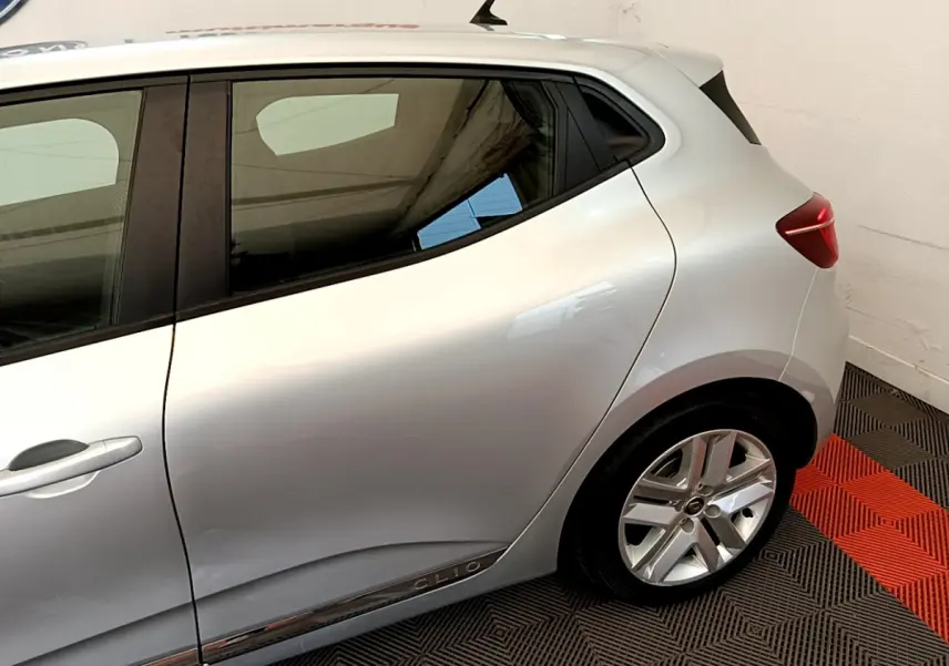 Vue latérale côté gauche d'une Renault Clio Business E-Tech hybride gris clair avec jantes alliage et poignées intégrées.