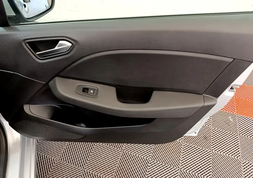 Gros plan sur la porte intérieure côté conducteur de la Renault Clio Business E-Tech hybride gris clair, avec poignée et commande de vitre.