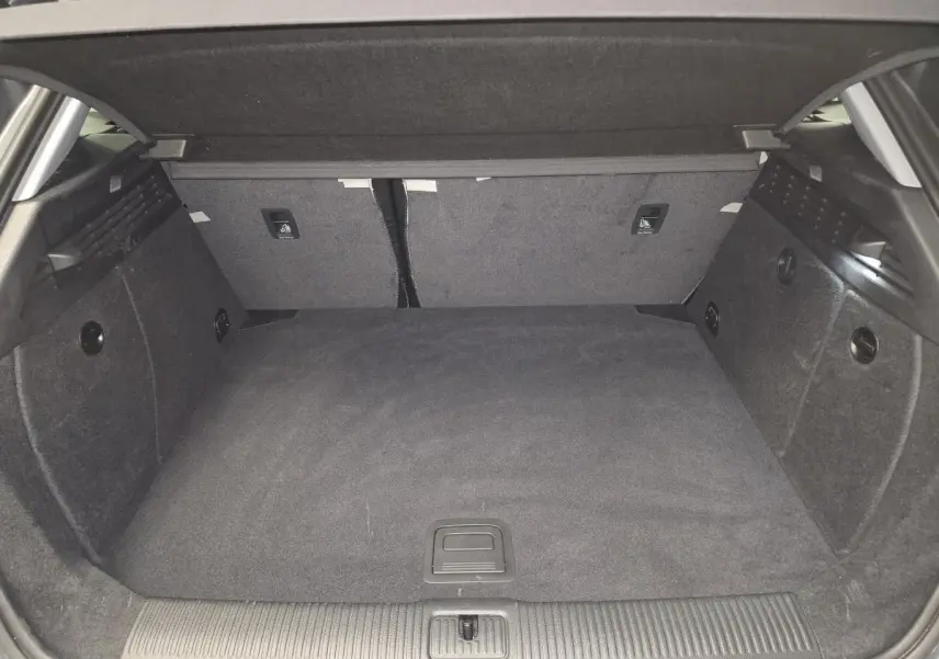 Coffre spacieux de l'Audi A3 Sportback gris, vue intérieure arrière avec tapis et banquette rabattable.