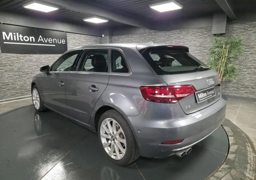 Audi A3 Sportback gris métallisé vue 3/4 arrière droit avec jantes aluminium 17 pouces en intérieur showroom