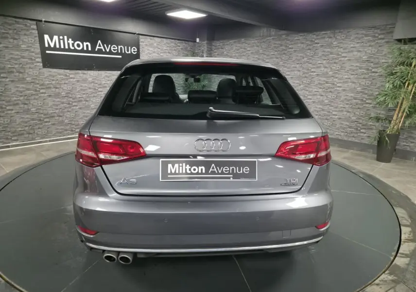 Vue arrière d'une Audi A3 Sportback gris métallisé avec double sortie d'échappement et logo TDI Quattro visible.