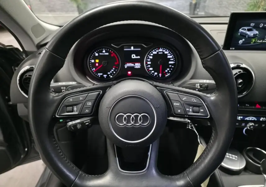 Vue intérieure centrée sur le volant cuir multifonction d'une Audi A3 Sportback 2017 avec tableau de bord et écran multimédia.