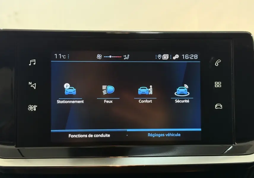Écran tactile central du tableau de bord de la Peugeot 208 blanc, affichant les réglages de conduite et sécurité.