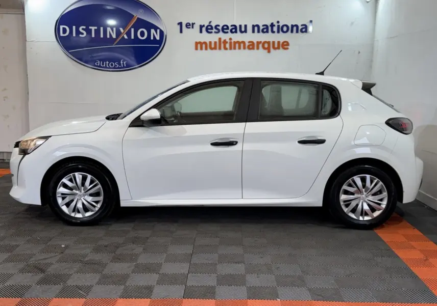 Profil droit d'une Peugeot 208 blanche 2021, compacte avec jantes alliage et feux arrière sombres en intérieur showroom.