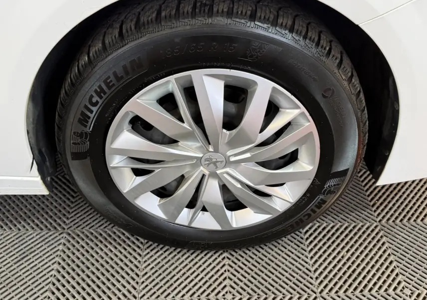 Gros plan sur la roue avant droite blanche d'une Peugeot 208 1.5 BlueHDi avec jante alu et pneu Michelin.