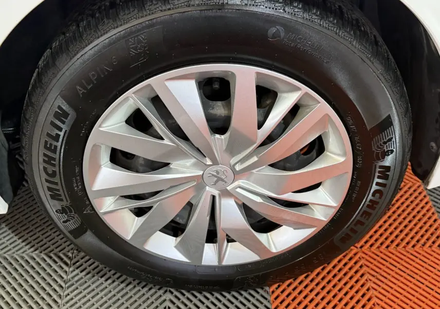 Gros plan sur la roue avant droite blanche d'une Peugeot 208 1.5 BlueHDi avec jante argentée et pneu Michelin.
