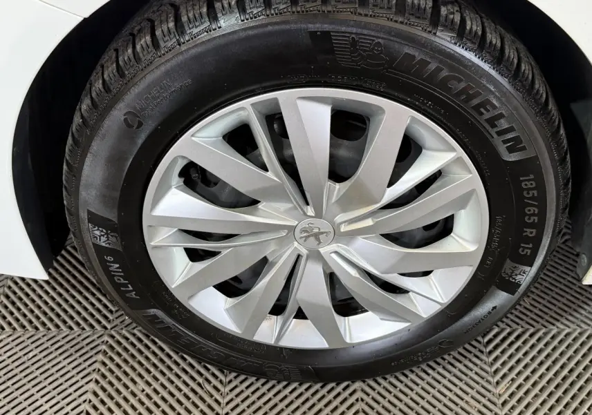 Gros plan sur la roue avant droite blanche d'une Peugeot 208 1.5 BlueHDi avec jante argentée et pneu Michelin.