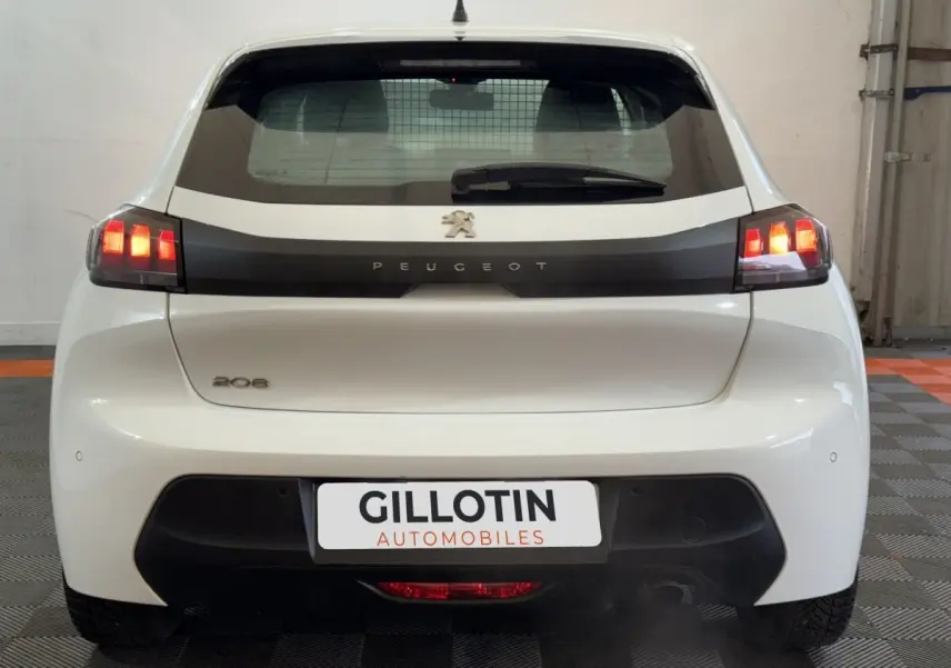 Vue arrière d'une Peugeot 208 blanche de 2021 avec feux LED allumés et logo Peugeot visible sur le hayon.