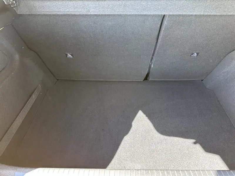 Coffre vide vu de dessus d'une Peugeot 208 jaune faro 2020, version 1.2 Pure Tech GT line, intérieur tissu gris.