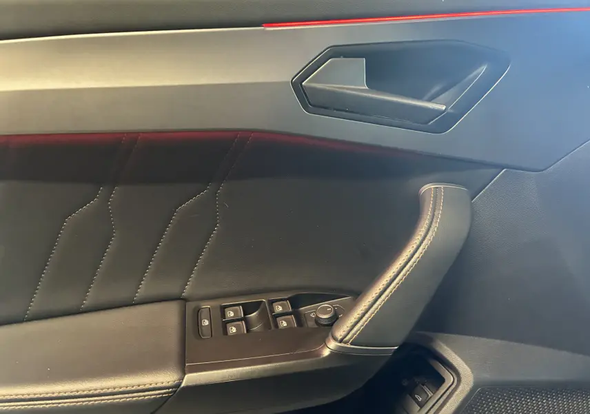 Gros plan sur la porte intérieure côté conducteur du CUPRA Formentor bleu, avec surpiqûres et commandes électriques.