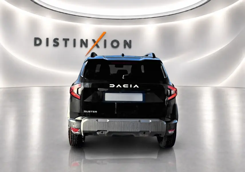 Vue arrière du Dacia Duster noir 2026 avec logo blanc et barres de toit visibles dans un showroom lumineux.