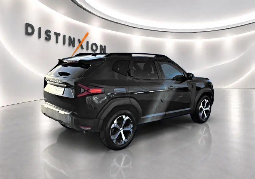 Vue 3/4 arrière droite d'un Dacia Duster noir 2026 avec jantes alu et barres de toit dans un showroom lumineux.