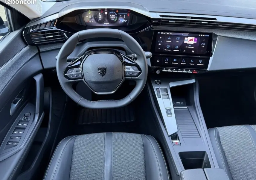 Vue intérieure centrée sur le volant cuir et tableau de bord numérique de la Peugeot 308 Hybrid 145 e-DCS6 Allure 2025.