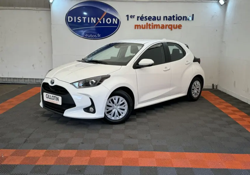 Toyota Yaris hybride blanche vue de 3/4 avant droit, avec phares ellipsoïdaux et jantes acier à enjoliveurs.