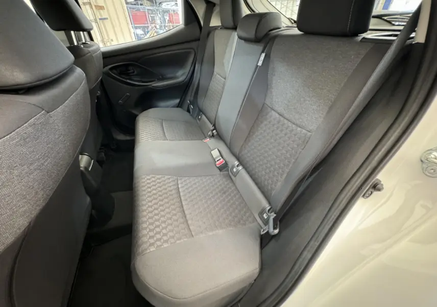 Vue intérieure côté droit sur la banquette arrière grise de la Toyota Yaris hybride blanche 2022 avec portes ouvertes.