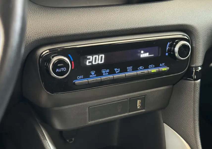 Gros plan sur la console centrale noire de la Toyota Yaris hybride 2022 avec affichage digital de la climatisation à 20°C.