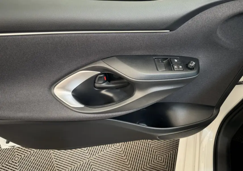 Poignée intérieure et commandes de fenêtre côté gauche de la porte avant d'une Toyota Yaris hybride blanche 2022.