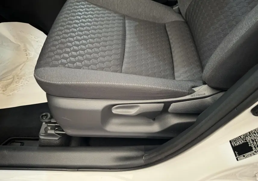 Gros plan sur le siège avant droit gris foncé de la Toyota Yaris hybride blanche, avec réglage manuel visible.