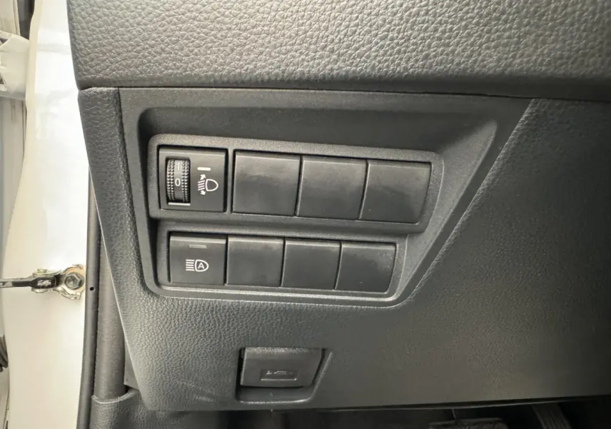 Panneau de commandes côté conducteur de Toyota Yaris blanche 2022, avec réglage phares et bouton auto start-stop.