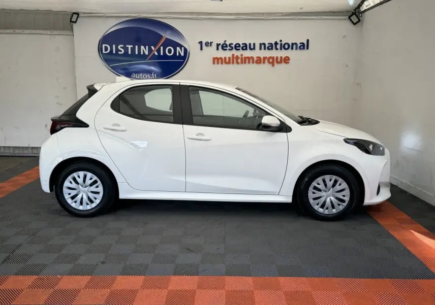 Profil côté droit d'une Toyota Yaris blanche 2022 hybride, avec jantes standard et toit noir contrastant.
