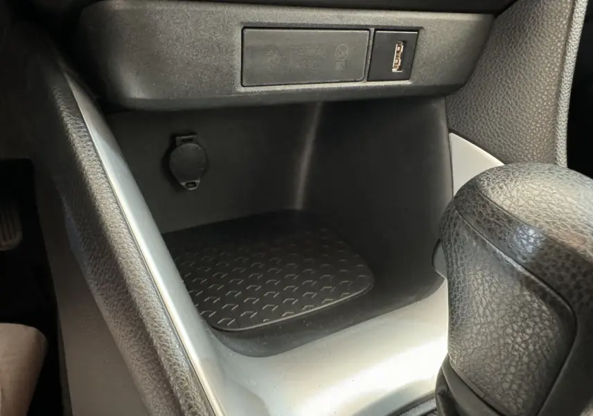 Gros plan sur la console centrale noire de la Toyota Yaris hybride 2022, avec prise USB et levier de boîte automatique.