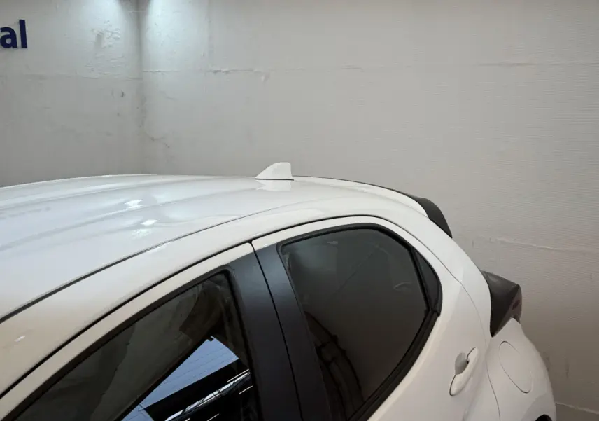 Vue du côté gauche arrière de la Toyota Yaris hybride blanche 2022 avec antenne requin sur le toit et vitres teintées.