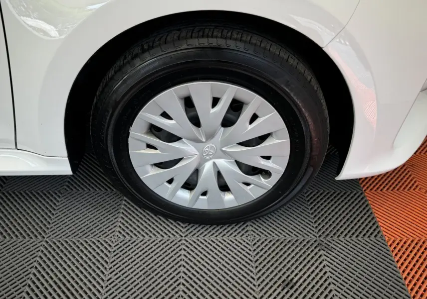 Gros plan sur la roue avant droite d'une Toyota Yaris blanche 2022 avec enjoliveur argenté au design en spirale.