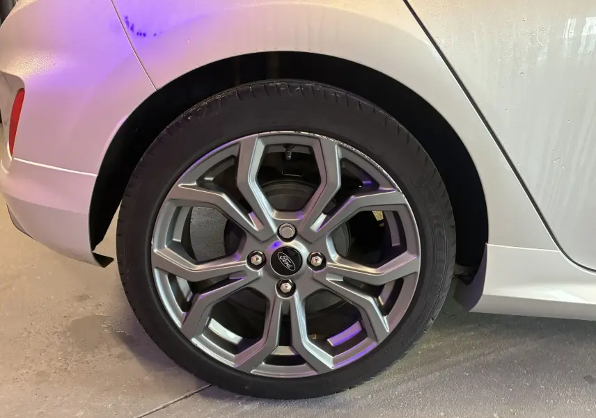 Gros plan sur la roue arrière gauche grise d'une Ford Fiesta 1.0 EcoBoost 95 ST Line avec jante alliage 17 pouces.