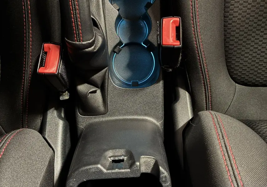 Vue plongeante sur la console centrale intérieure de la Ford Fiesta gris, avec levier de frein à main et porte-gobelets bleutés.